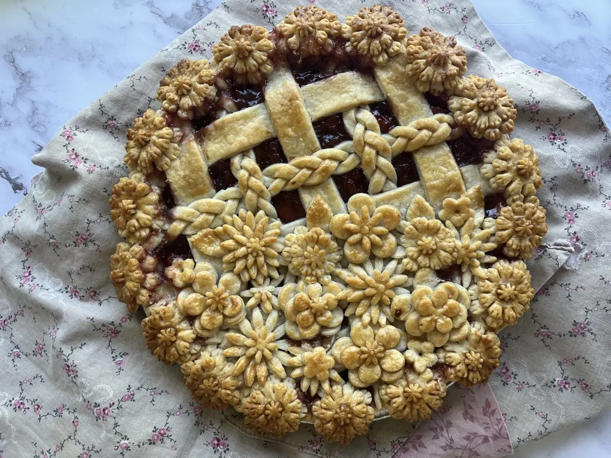 Berry pie with ornate floral crust on a vintage floral cloth